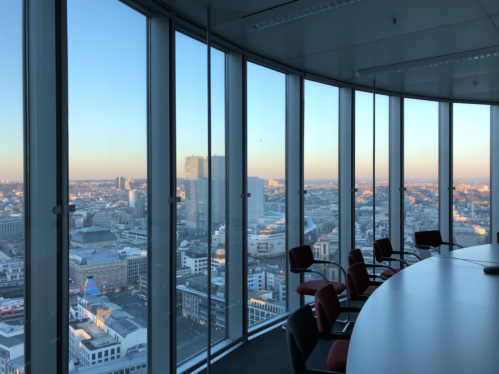 An image of chairs and a table in a room with large windows