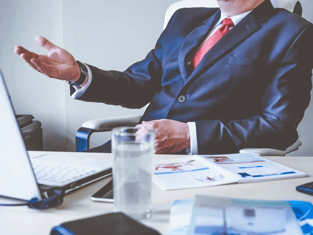 An image of a man in a suit sitting in front of a laptop